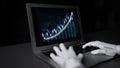 Futuristic robot hands interacting with a laptop displaying a dynamic line graph, symbolizing advanced technology and Royalty Free Stock Photo