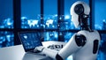 Futuristic robot working on laptop with data projections in modern office environment Royalty Free Stock Photo