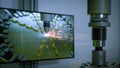 A futuristic simulation on a large screen depicting a laser welding process with animated graphics showing the flow of