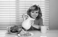 Fuuny little boy pouring whole cows milk for breakfast. Funny blonde little boy having breakfast. Milk, vegetables and