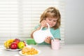 Fuuny little boy pouring whole cows milk for breakfast. Healthy nutrition for children. Cute boy enjoy eating for