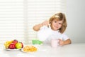 Fuuny little boy pouring whole cows milk for breakfast. Kid preteen boy 7, 8, 9 years old eating healthy food vegetables