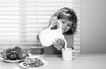 Fuuny little boy pouring whole cows milk for breakfast. Schoolkid eating breakfast before school. Portrait of child sit