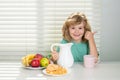 Fuuny little boy pouring whole cows milk for breakfast. Schoolkid eating breakfast before school. Portrait of child sit