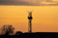 5G controversial radio mobile telephone broadcast transmitter mast silhouette at golden hour sunset. Summer sky with clouds