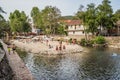 GÃ³is, PORTUGAL - June 17, 2022 - Stone wall next to the Ceira river with a sand island and people at leisure and Roman bridge