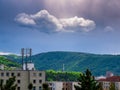 5G telecommunication transmitter on the roof of an apartment building with clouds and sunlight in the dark sky Royalty Free Stock Photo