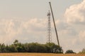 5G transmission tower is erected on a field with the help of a huge crane