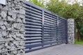 Gabion. Automatic entrance gate used in combination with a wall made of gabion