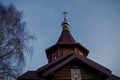 Gable roof of wooden Orthodox Church with log walls, six-sided tower, blue dome and gilded Orthodox cross with icon above entrance Royalty Free Stock Photo