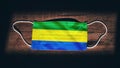 Gabon National Flag at medical, surgical, protection mask on black wooden background. Coronavirus CovidÃ¢â¬â19, Prevent infection,
