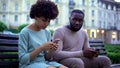 Gadget addicted couple chatting in their smartphones, sitting on bench, ignore Royalty Free Stock Photo