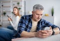 Gadget addiction or marriage infidelity. Mature man and woman overusing cellphones, playing games, texting lovers