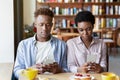 Gadget addiction and phubbing. Young black couple having dull date, stuck in smartphones, ignoring each other at cafe Royalty Free Stock Photo