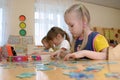 Girls at the table play puzzles Royalty Free Stock Photo