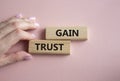 Gain trust symbol. Wooden blocks with words Gain trust. Beautiful pink background. Businessman hand. Business and Gain trust