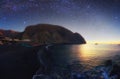 Galaxy over  Perissa beach with Black volcano sand of at summer sunset. Royalty Free Stock Photo