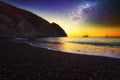 Galaxy over  Perissa beach with Black volcano sand of at summer sunset. Royalty Free Stock Photo