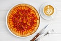 Galette with apricots and strawberries. Homemade pastry and cup of coffee on white wooden table.