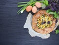 Galette with egg, green onion, cheese and crispy vegetarian dough on a black wooden table and wooden background.