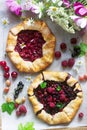 Galette pies with juicy berry filling, berries and wild flowers on a wooden background. Rustic style. Royalty Free Stock Photo
