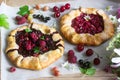 Galette pies with juicy berry filling, berries and wild flowers on a wooden background. Rustic style. Royalty Free Stock Photo