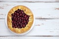 Galette with ripe red cherry filling on white background. Homemade sweet open pie on Provence style background. Top view. Space Royalty Free Stock Photo