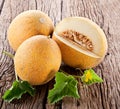 Galia melons with green leaves on wooden table Royalty Free Stock Photo