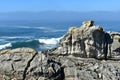 Cliff with waves breaking, mist and blue sky. Galicia, Spain.