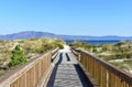 Beach with boardwalk and vegetation in sand dunes. Small mountain and blue sea, clear sky. Sunny day, Galicia, Spain. Royalty Free Stock Photo