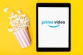 Popcorn bucket and tablet with Amazon prime video logo on yellow background. Top view Royalty Free Stock Photo