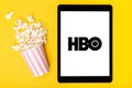 Popcorn bucket and tablet with HBO logo on yellow background. Top view Royalty Free Stock Photo