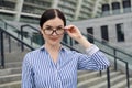 Gallant beauty lady in shirt with white cuffs on her sleeves against the background of the city