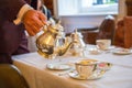 Gallant waiter pouring the tea, traditional English afternoon tea ceremony