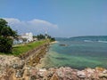 Galle, Sri Lanka - March 12, 2022: View of the white stone lighthouse and the fortress wall along the ocean in Galle Fort. Copy