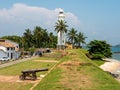 Galle, Sri Lanka - March 12, 2022: View of the white stone lighthouse and the old artillery gun in the Galle Fort. Tourists walk Royalty Free Stock Photo