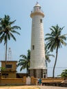 Galle, Sri Lanka - March 12, 2022: View of the white stone lighthouse and tall coconut palms at Galle Fort. Vertical Royalty Free Stock Photo