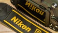 Galle, Sri Lanka - 02 17 2021: Nikon neck strap in front of the camera display and reflection, yellow letters branding in nylon