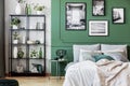 Gallery of black and white poster on green wall behind king size bed with pillows and blanket