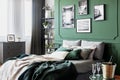 Gallery of black and white poster on green wall behind king size bed with pillows and blanket Royalty Free Stock Photo