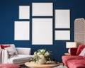 Gallery wall in living room interior mock-up with red sofa, wooden table and rattan home decoration in dark blue background Royalty Free Stock Photo