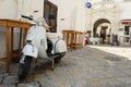 White scooter Vespa Piaggio on the street in downtown white city Gallipoli, Salento