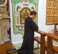 Young Catholic priest kneeling in prayer.