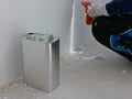 A gallon of thinner placed next to old concrete wall, while a painter is removing sticky rough glue and tape remain on the wall,