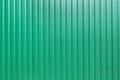 Galvanized iron fence with corrugated vertical stripes closeup.