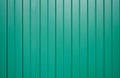 Galvanized iron fence with corrugated vertical stripes of green as fence wall