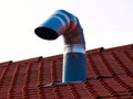 Galvanized metal gooseneck vent and brown clay tile sloped roof ridge. Royalty Free Stock Photo