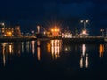 Galway - Ireland / 10/08/2020: Commercial ships in Galway Harbor illuminated at night. Reflection in the water. Night scene