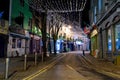 Galway, Ireland - 11/26/2020: Night scene, decorated and illuminated for Christmas Shop street, Rubbish bags in the street for