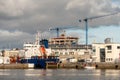 Galway/Ireland- 10/11/2020: Small yacht sailing into Galway harbor passing by commercial ship. Construction site of Bonham Quay in